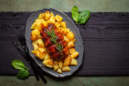 Baked duck roulade stuffed with meat and oranges and baked potato, decorated with rosemary. Homemade tasty dinner with table settings. Directly above.の写真素材
