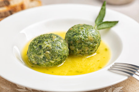 Close-up of canederli with spinach served in soup - bread dumplings made from dried bread rolls, milk, spinach, cheese and eggs. Trentino food, Italy. Selective focus.の写真素材