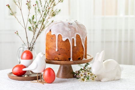 Easter food composition. Cake, sweet bread decorated with icing, red coloured eggs, spring flowers,...