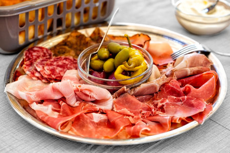 Italian Lunch sliced meat affettati, cold cuts, luncheon, prosciutto, cured pork meat, salame and pickles on a plate, or Spanish tapas.の写真素材