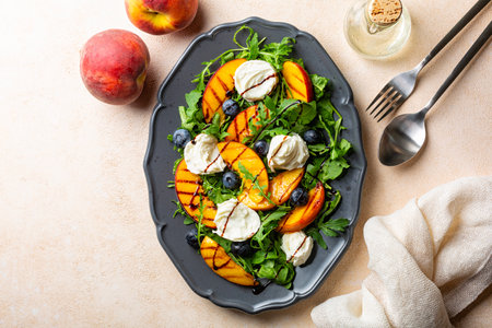 Grilled peach salad with arugula, mozzarella buffalo cheese, blueberries, balsamic sauce. Directly above, beige background, copy space.の写真素材