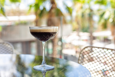 Aperitif with CaffÃ¨ shakerato in a tall glass, in an outdoor italian cafe, palms on background....
