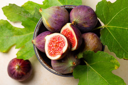 Bowl with fresh ripe purple figs fruit with green leaves. Top views.の写真素材
