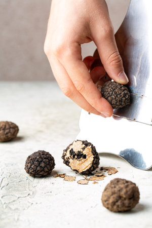 Hands grating delicious black truffles black italian truffle, Tuber Aestivum with special slider or knife. Close up, vertical image.の写真素材