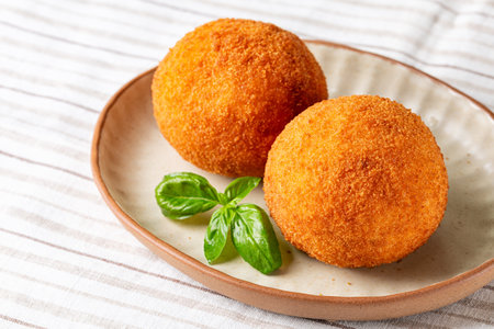 Italian rice balls arancini, that are stuffed, filled with ham ham and mozzarella, coated with breadcrumbs and deep fried. Sicilian snacks, street food.の写真素材