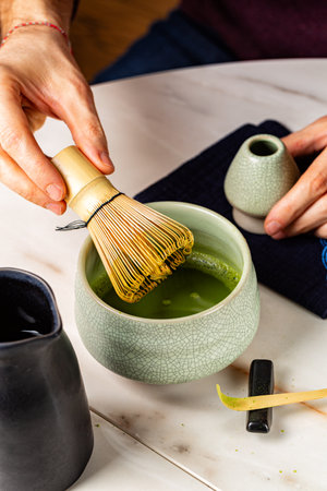 Man cooking green matcha tea  in the traditional Japanese ceremony. Bamboo whisk, spoon, or shashaku, tea into a heated tea bowl known as a chawan. Vertical image..の写真素材