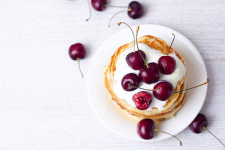 pancake with yogurt and cherry on a white background top view, space for text