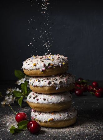 some delicious donuts at each other with cherry berry on dark background colorful sprinkles front artの写真素材