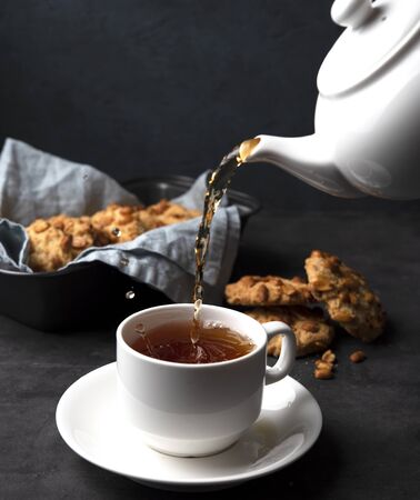 white cup of tea and teapot pour  cookies handmade close upの写真素材