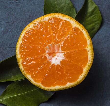 one half sweet fresh tangerine macro leaf on dark blackground top viewの写真素材