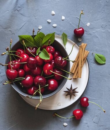cherry berry on gray bowl with flowers on gray table cinamon and anis top view summer morning shaddowの写真素材