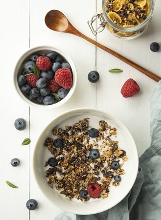 breakfast granola with milk blueberry raspberry cornflakes top view wood backgroundの写真素材