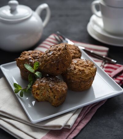 Some carrot muffins with nuts and mint  white cup of tea breakfast bakeryの写真素材