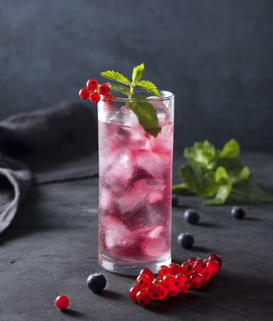 fresh cold glass berry drink  with ice blueberry red currant and mint dark backgroundの写真素材