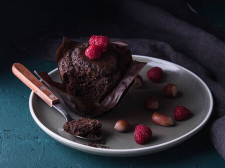 sweet chocolate muffin with raspberry and spoon on plate dark background close upの写真素材