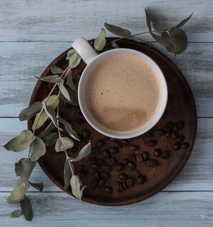 fresh coffee latte, on brown wood plate with coffee beans and flowers, top view rustic backgroundの写真素材