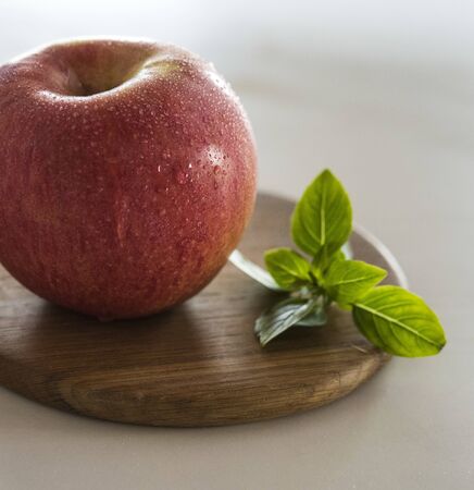 fresh sweet red apple wet on brown wood board with mint window morning lightの写真素材