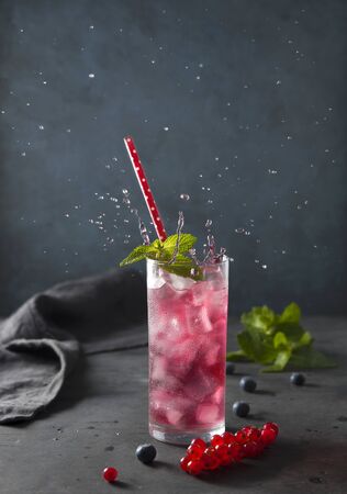 fresh cold glass berry drink  with ice blueberry red currant and mint dark background splashの写真素材