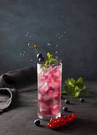 fresh cold glass berry drink  with ice blueberry red currant and mint dark background splashの写真素材