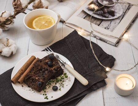 sweet chocolate brownie cup of tea with lemon candles and book hygge mood flat lay autumnの写真素材