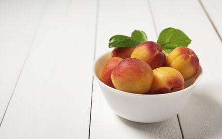 sweet delicious apricot on bowl white wood table summer fresh fruitの写真素材