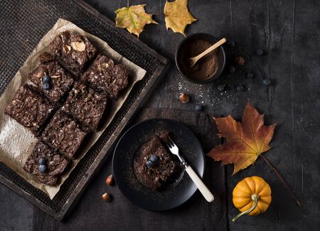 sweet handmade chocolate brownie with  blueberries pumpkin yellow folliage dark background autumn mood top viewの写真素材