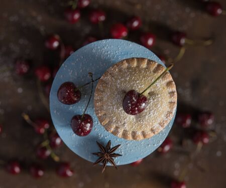 sweet mini cherry pie on blue wood  stand  on vintage background top view close upの写真素材