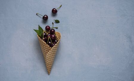 fresh red cherry berry in  waffle cone  on blue background top view copy space free textの写真素材