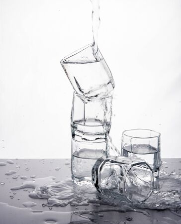 some glasses with water spill on mirror table control light front black whiteの写真素材