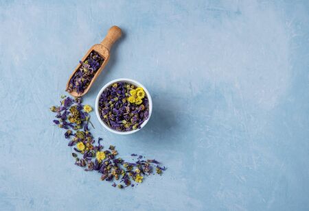 aromatic herbal dry tea lavender and chamomile loose near white cup on blue wood table top viewの写真素材