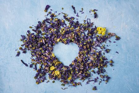 aromatic herbal dry tea lavender and chamomile loose heart  on blue wood table copy space top viewの写真素材
