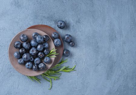 fresh sweet blueberries in gray plate on pure blue wood table top view copy space の写真素材