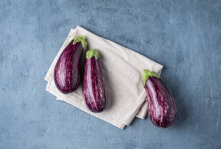 three juicy eggplants graffiti  lie on a gray napkin on  blue concrete table top view copy space の写真素材