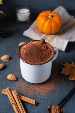 Aroma spice coffee latte drink with pumpkin,  milk foam, cinammon and chocolate  on the dark blue table.Autumn morning. Image in vertical orientationの写真素材