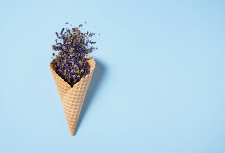 dry cornflower tea falls out of a waffle cone on a blue background. Top view and copy spaceの写真素材