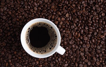 fresh cup of coffee espresso on coffee beans brown seed texture background full wallpaper. Top view and copy space の写真素材