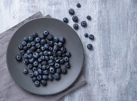 Fresh and sweet blueberry in gray  plate and napkin on old vintage  white wood background. Top view and copy space.の写真素材