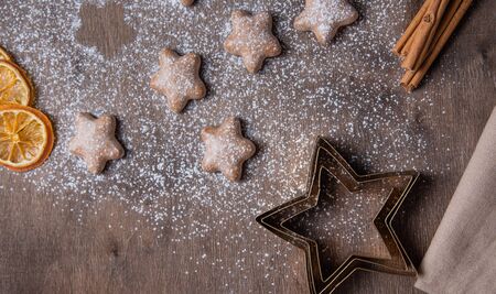 Aroma Christmas gingerbread stars with orange and cinnamon in powdered sugar on an old wooden brown table. Homemade cake. Top viewの写真素材
