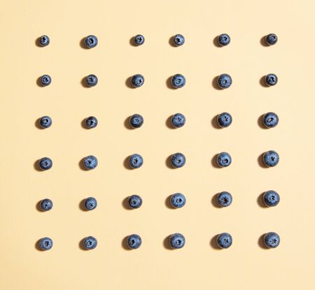 graphic pattern of fresh juicy blueberries is laid out on a yellow background. Top view and flat layの写真素材