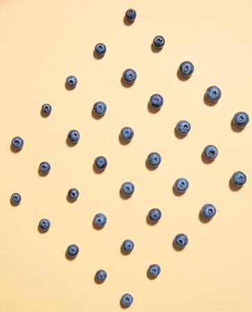 graphic pattern of fresh juicy blueberries is laid out on a yellow background. Top view and flat layの写真素材