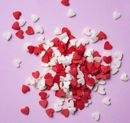 pastry sprinkles in the form of hearts are red and white scattered on a pink background. Valentine's day. Macro viewの写真素材