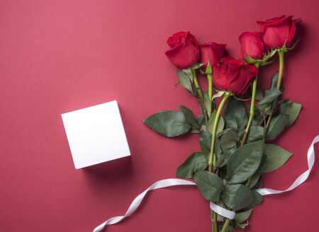 A beautiful and delicate bouquet of red roses lies on a red background with white pure box present. Valentines day. Top view and copy space
の写真素材