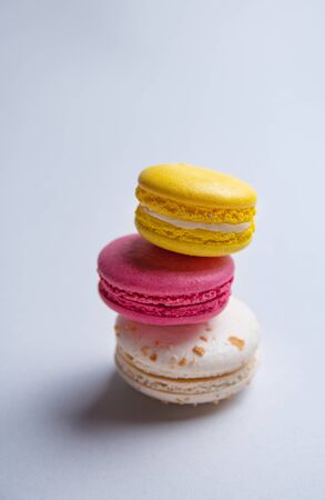a stack of three delicious macaron and pink, white and yellow on a gray background. Image is close up, macro and front viewの写真素材