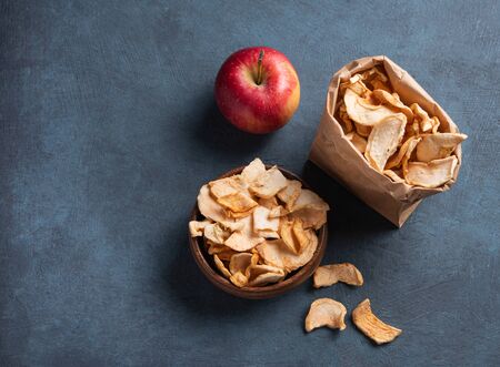 sweet homemade Apple chips dried with cinnamon in wood bowl on dark blue background. Vegan and dietary product. Top view and copy spaceの写真素材