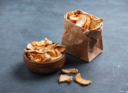 sweet homemade Apple chips dried with cinnamon in wood bowl on dark blue background. Vegan and dietary product.の写真素材