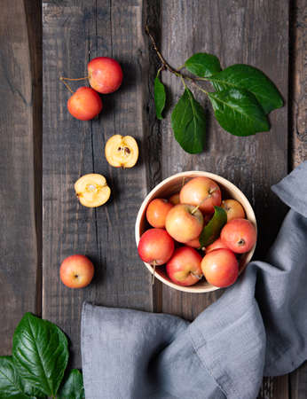 juicy mini apples in a bowl with linen towel on a old wooden background. Rustic style and top viewの写真素材