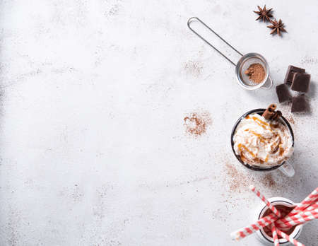 coffee latte with creamy caramel cream, red papper tube and cinnamon in a white mug on a white table. Top view and copy spaceの写真素材