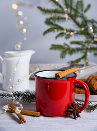 Christmas tea with cinnamon and spices in a red mug with homemade cookies on a gray background with a Christmas tree and a garland. Front and macro viewの写真素材