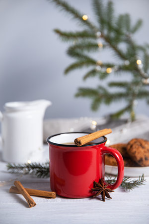 Christmas tea with cinnamon and spices in a red mug with homemade cookies on a gray background with a Christmas tree and a garland. Front viewの写真素材