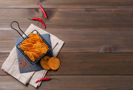 Mexican  chips nachos with paprika and chili pepper on brown wood background. Top view and copy spaceの写真素材